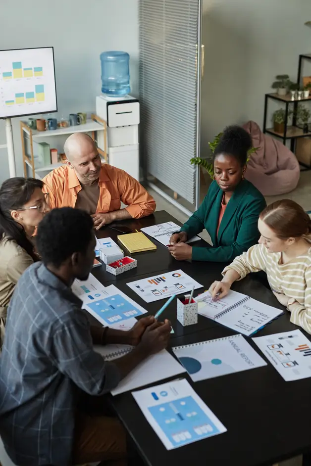 Team gathered around a table reviewing printed marketing materials during Alchemy training